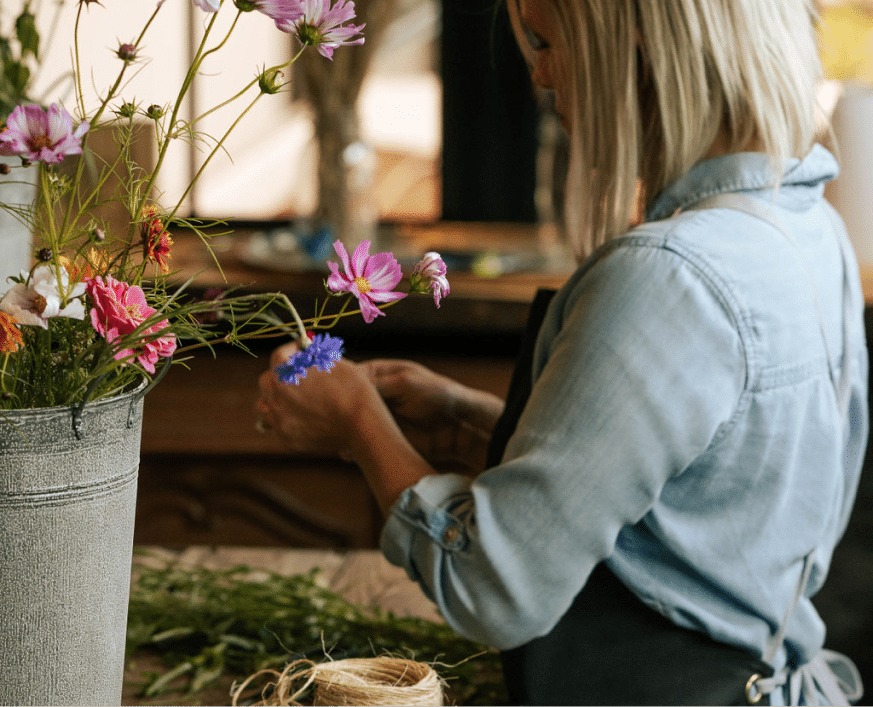 Florist arranging colorful rustic bouquet with twine in a cozy flower workshop.