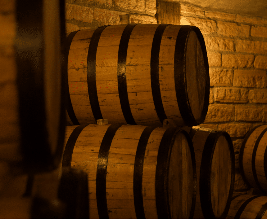 Warm oak barrels stacked in a rustic brick cellar with soft golden lighting.