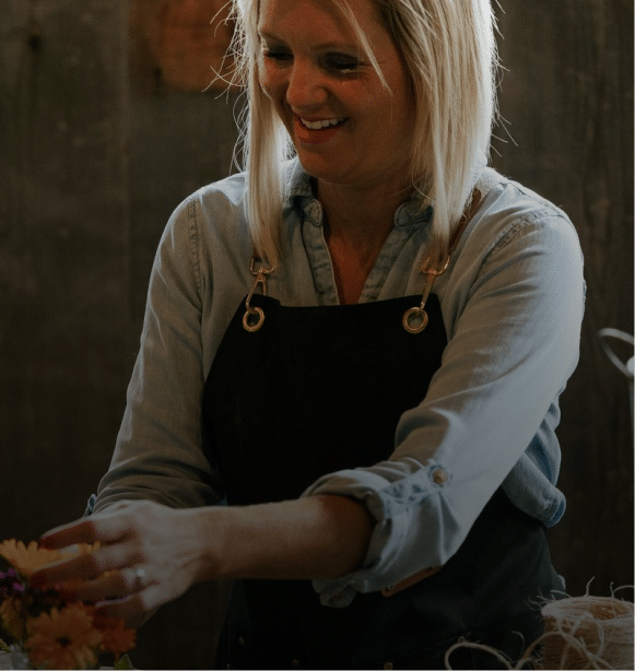Smiling florist arranging colorful flowers in a cozy rustic workshop.