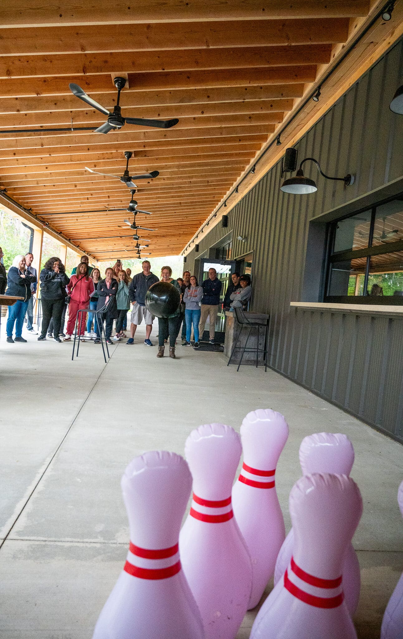 Employees enjoying an outdoor corporate event with inflatable bowling under a shaded pavilion.