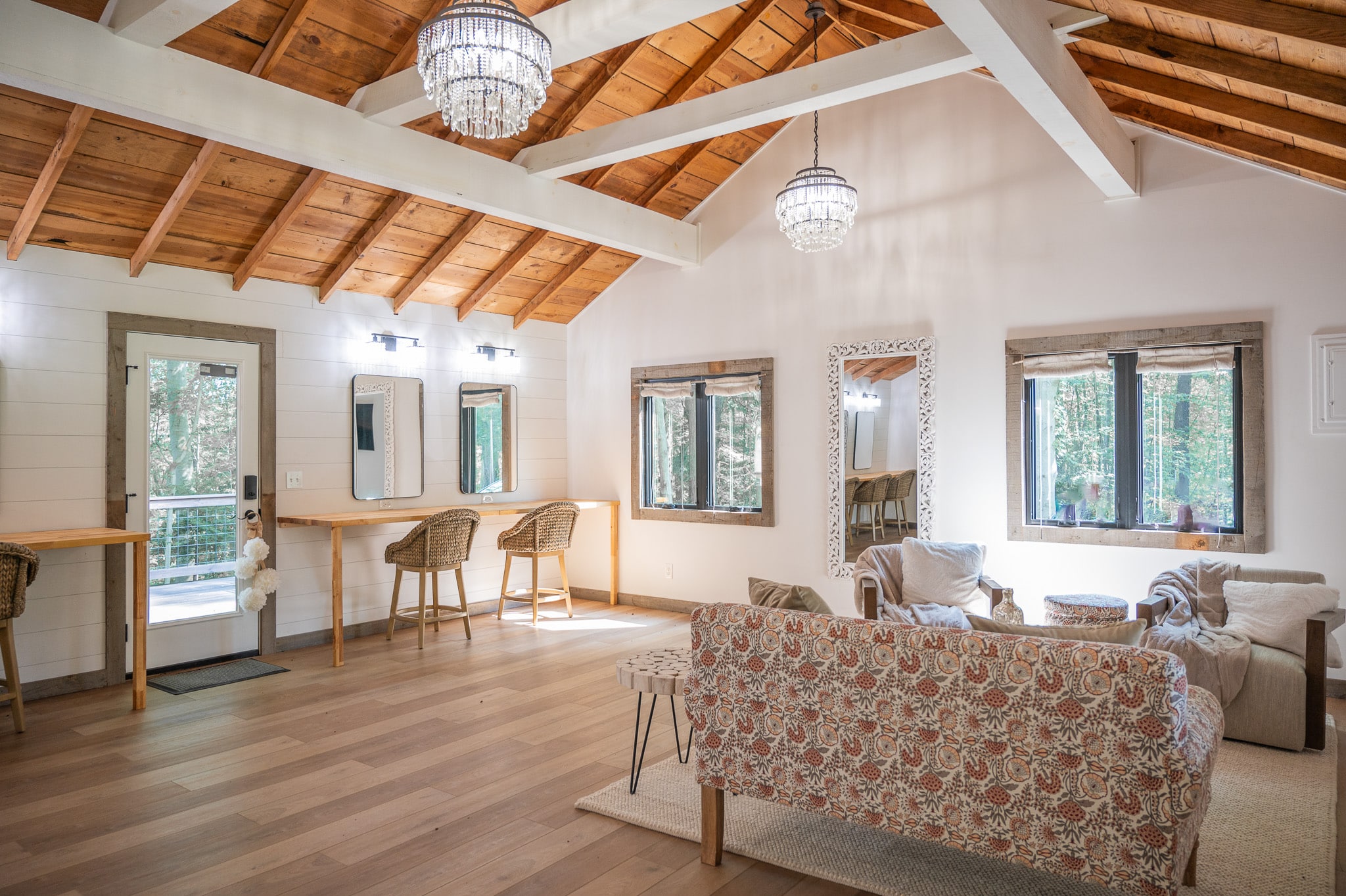 Bright rustic living room with exposed wooden beams, floral sofas, and elegant chandeliers.
