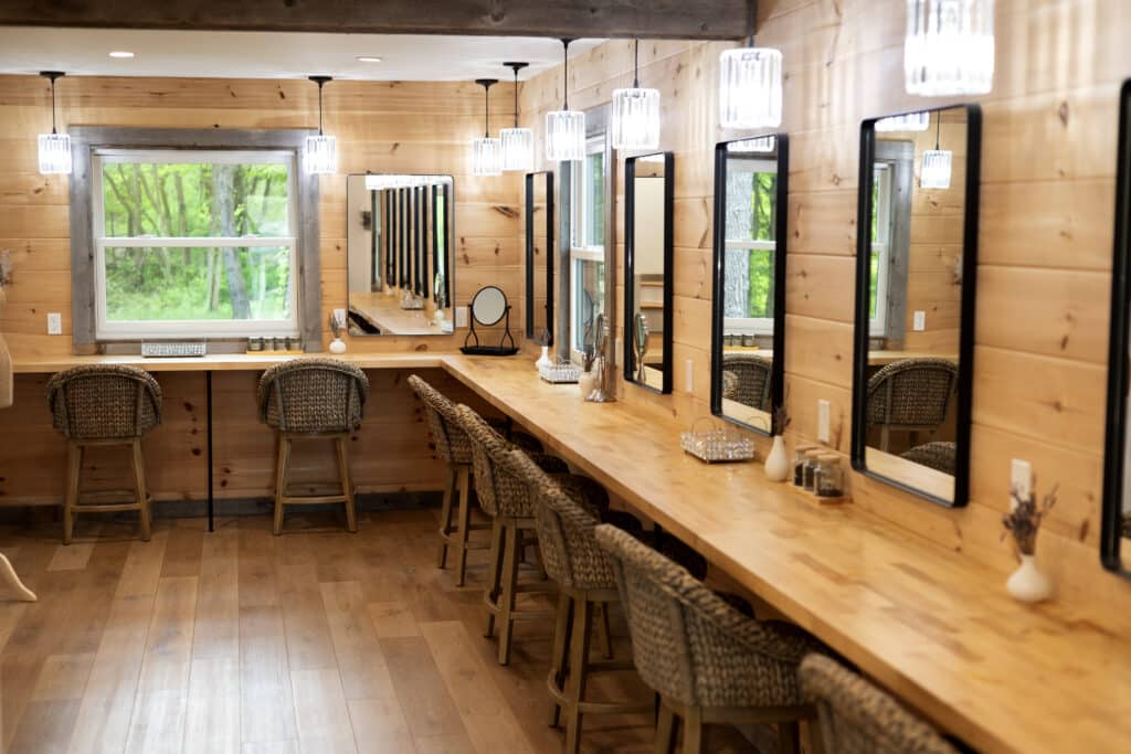 Rustic bridal dressing room with wooden vanities, warm lighting, and elegant mirrors for wedding prep.