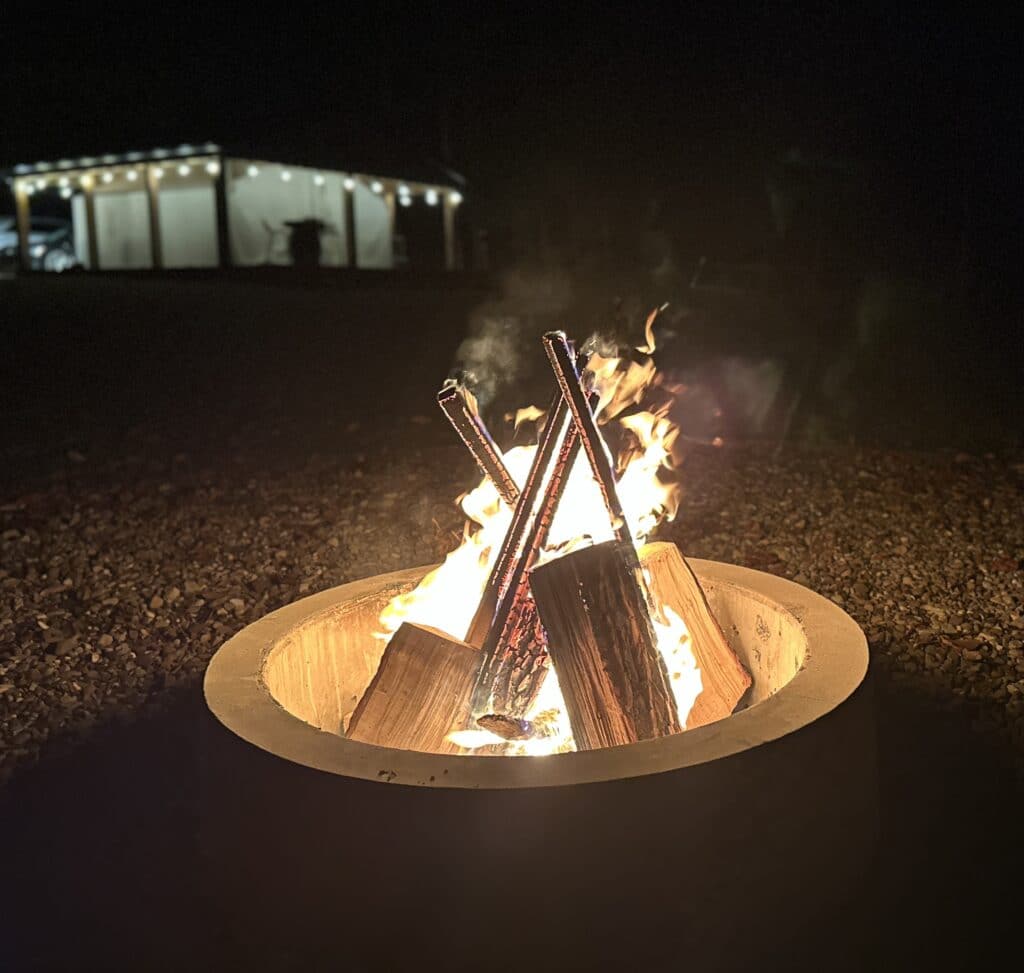 Warm campfire glowing at night with cozy lights creating a peaceful outdoor atmosphere.